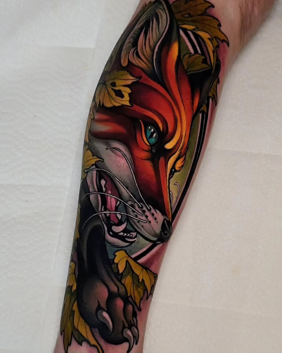 Vibrant colored tattoo on forearm featuring a red and orange bird's head with yellow wings, surrounded by decorative butterflies and flourishes.