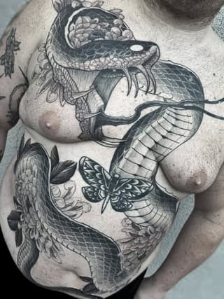 Large detailed chest tattoo featuring an orca whale with ornate floral and scroll details, accompanied by a moth and additional marine elements in black ink.