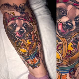 Colorful leg tattoo featuring two smiling dog faces with crowns, ornate gold and blue decorative elements, and pink floral accents.