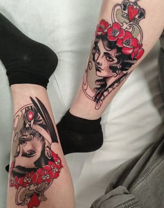 Two legs display matching tattoos featuring vintage female portraits with red flowers, ornamental frames, and red gemstone accents.