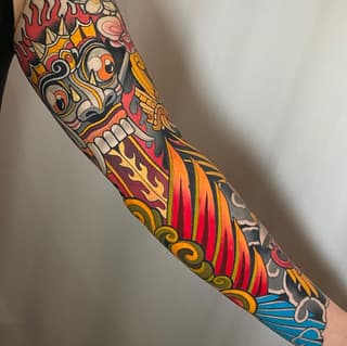 Colorful full-length arm sleeve tattoo featuring a skull with flames, ornamental scrollwork, and water waves in red, orange, yellow, black, and blue.