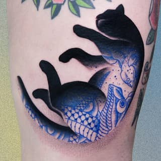 A mermaid tail with black upper body and blue-scaled lower half featuring decorative patterns wraps around the upper leg and thigh.