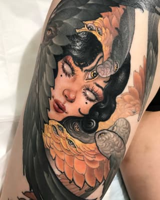Colorful shoulder tattoo featuring a woman's profile with closed eyes, red lips, black hair, and bird imagery in orange and gray tones.