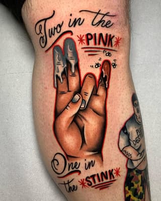 Peace sign hand gesture with red outline and text reading "Two in the *PINK* One in the *STINK*" on upper thigh.
