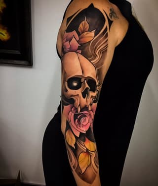 Full-sleeve arm tattoo featuring a skull with roses and flowing hair elements in orange, pink, red, and black colors.