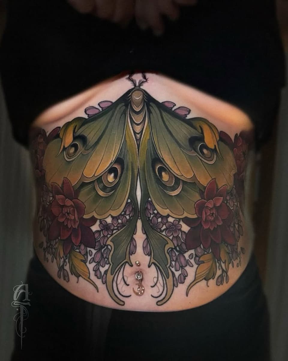 Large symmetrical moth with gold and olive wings, burgundy flowers, and ornamental details centered on the chest and abdomen.