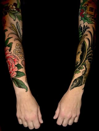 Two full-length sleeves featuring botanical elements including pink roses, daisies, birds, and decorative foliage in red, green, gold, and black colors on pale skin.