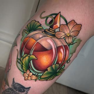 Colorful tattoo on an arm featuring a glowing red and orange orb surrounded by green vines, orange flowers, and a small hat with a feather on top.