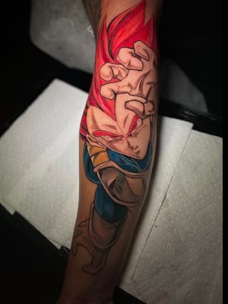 Colorful tattoo on the calf featuring a character with red spiky hair, clenched fists, and blue clothing against a skin-tone background.