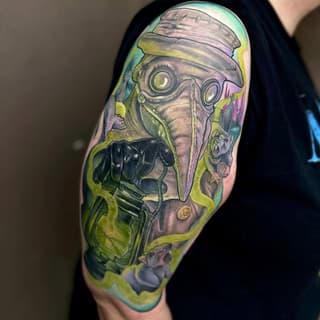 Colorful upper arm tattoo depicting a figure wearing goggles and headwrap with mechanical elements, rendered in yellow-green, pink, and gray tones.