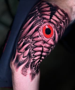 Anatomical skeleton wing with a striking red iris eye tattoo on the upper arm, rendered in pink and black ink.