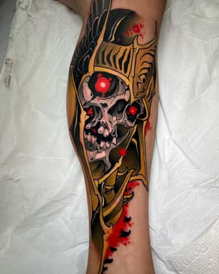 Skull with glowing red eyes and ornamental gold designs in black, red, and gold ink on a calf.