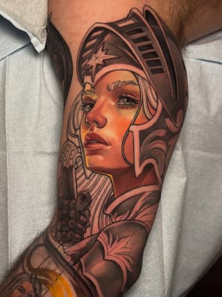 Colorful portrait tattoo of a woman wearing an ornate Egyptian headdress with a star symbol, featuring warm orange and brown tones on the upper leg.