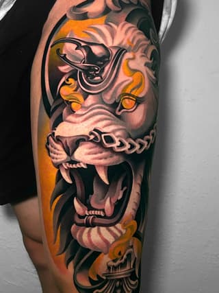 Colorful sleeve tattoo featuring stacked demon and skull faces with orange flames, ornamental details, and black outlines on the upper arm.