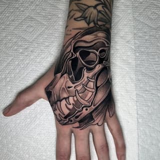 Skull with sunglasses and flowing hair tattoo on hand and forearm in black and gray ink with dotwork shading.