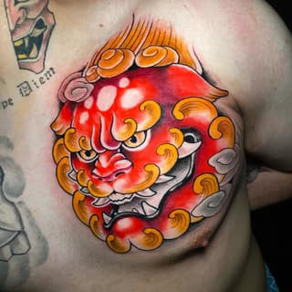 Red demon or oni mask face with golden curled horns and decorative scrollwork on chest, featuring white highlight details and gradient shading.