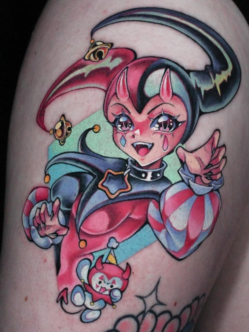 Colorful character tattoo on upper arm featuring a pink-skinned figure with pointed ears, black hair with headband, red and blue outfit, and small companion creature below.