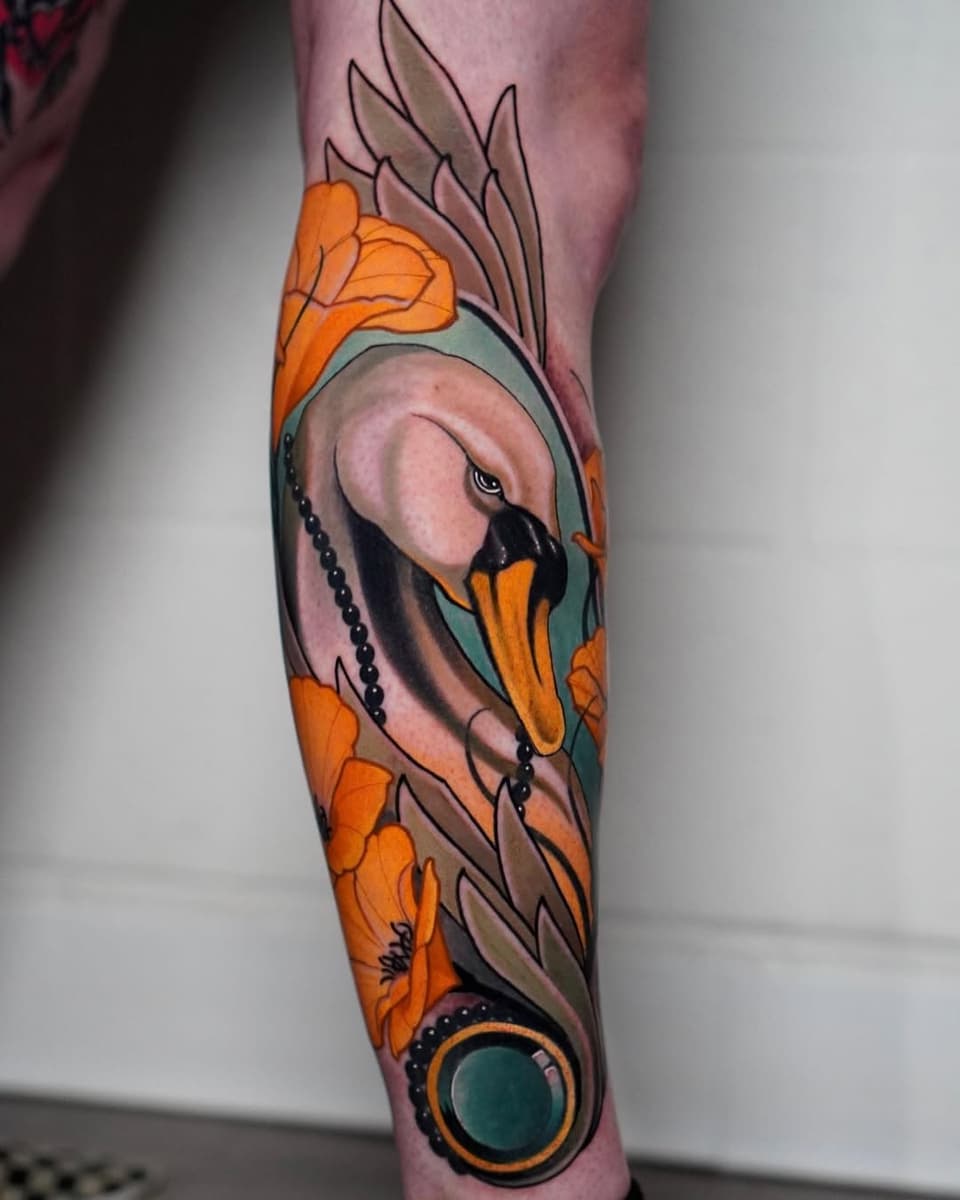 Colorful leg tattoo featuring a bird with orange and teal markings surrounded by orange flowers and decorative leaf elements on the calf.