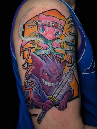Colorful shoulder tattoo featuring a pink character with a headband and a purple demon face below, holding a sword, with orange and yellow background elements.