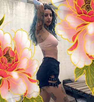 Woman displaying colorful floral and decorative tattoos on her arms, torso, and legs in shades of red, yellow, and black.