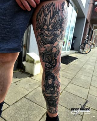 Full leg sleeve tattoo featuring an anime character with spiky hair at top, a female character lower on the calf, rendered in black ink on tan skin.
