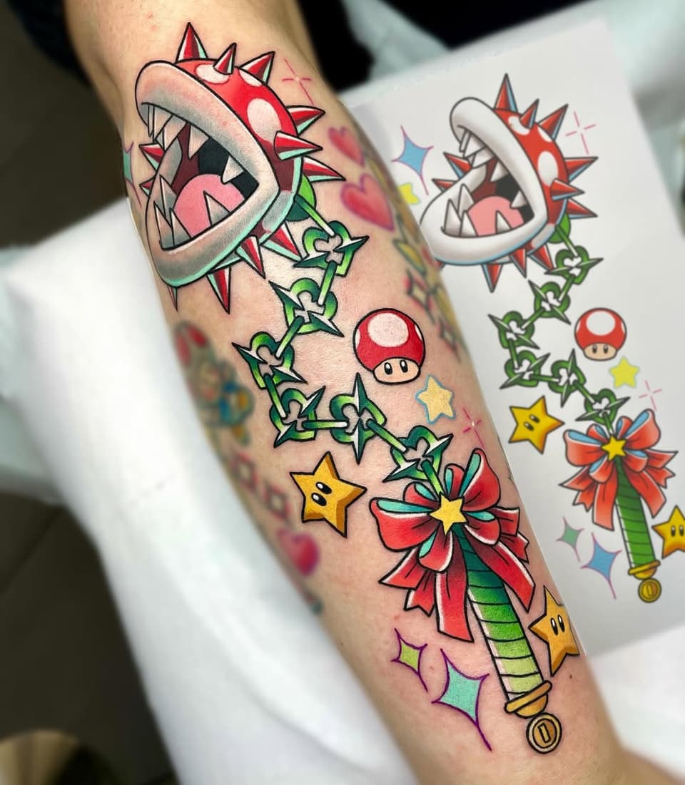 Colorful Mario Piranha Plant tattoo on forearm featuring green vines, red spikes, yellow stars, mushroom, and flower elements with design reference sheet.