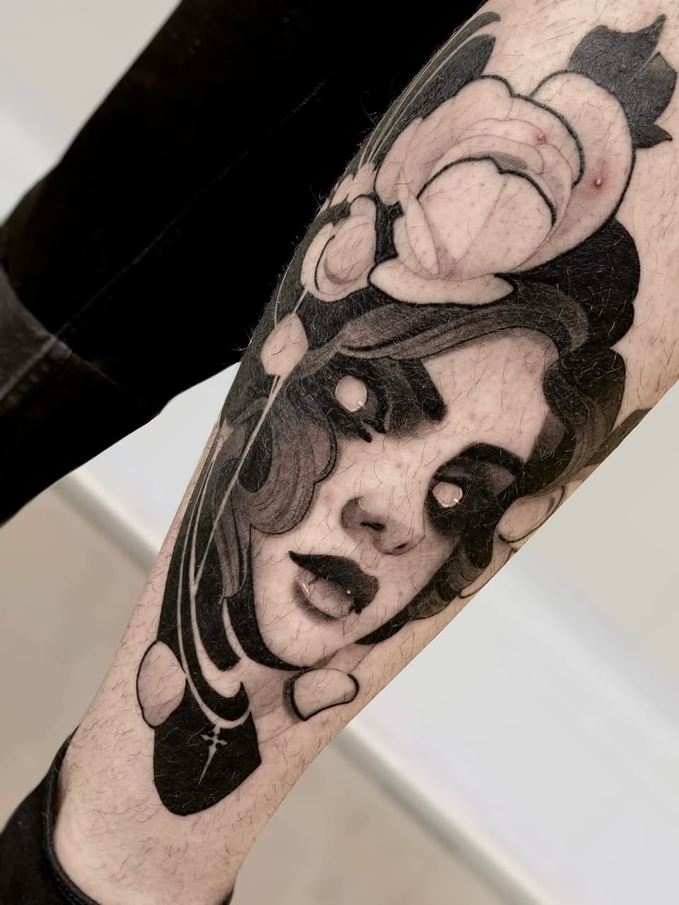 Two expressive faces stacked vertically on the forearm in black and gray ink, featuring detailed shading and emotional expressions.