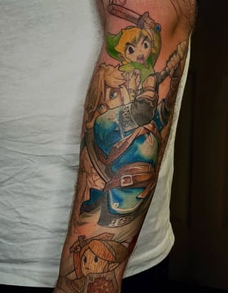 Colorful arm tattoo featuring a blonde character in green tunic with sword, brown-haired figure in blue outfit, and smaller character below, displayed on male forearm.