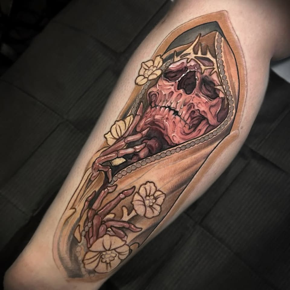 Skull tattoo with burgundy and tan shading, cream flowers, and decorative beading on the forearm.