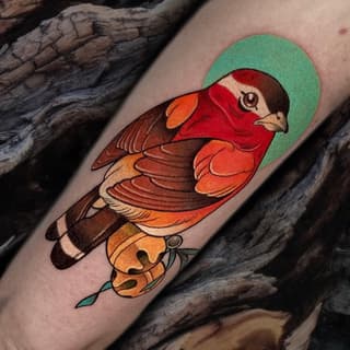Colorful tattoo of a red-headed duck with brown and orange plumage and a green halo, positioned on the forearm against wooden background.