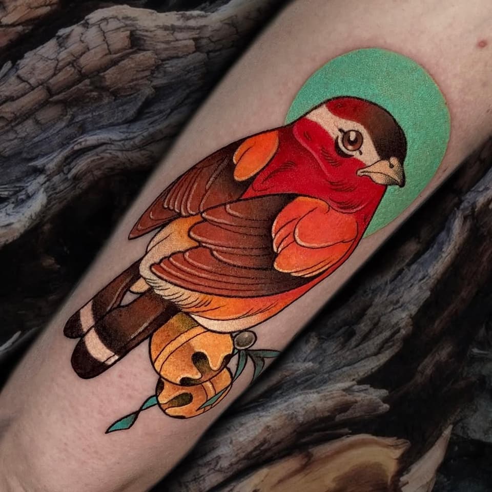 Colorful tattoo of a red-headed duck with brown and orange plumage and a green halo, positioned on the forearm against wooden background.