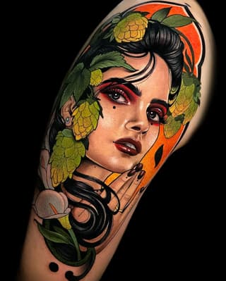 Portrait tattoo of a woman's face with hops flowers framing her head, featuring red and orange background, black hair, and decorative headphones at the neck.