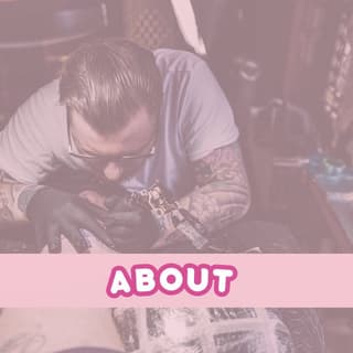 Tattoo artist working on a detailed arm piece featuring intricate designs in dark ink on a client's upper arm and shoulder.