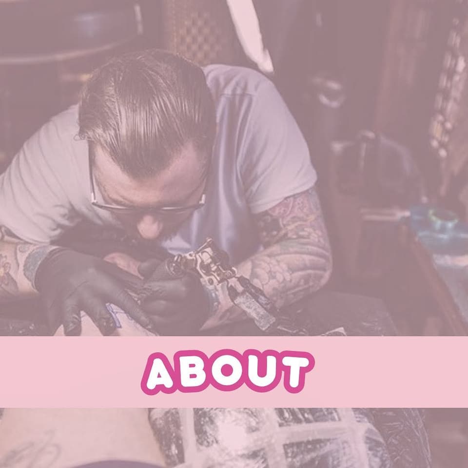 Tattoo artist working on a detailed arm piece featuring intricate designs in dark ink on a client's upper arm and shoulder.