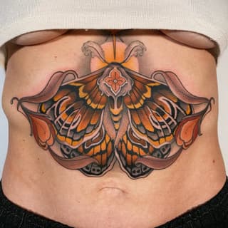 Colorful moth tattoo with orange and yellow wings, ornate details, and decorative flourishes centered on the chest.