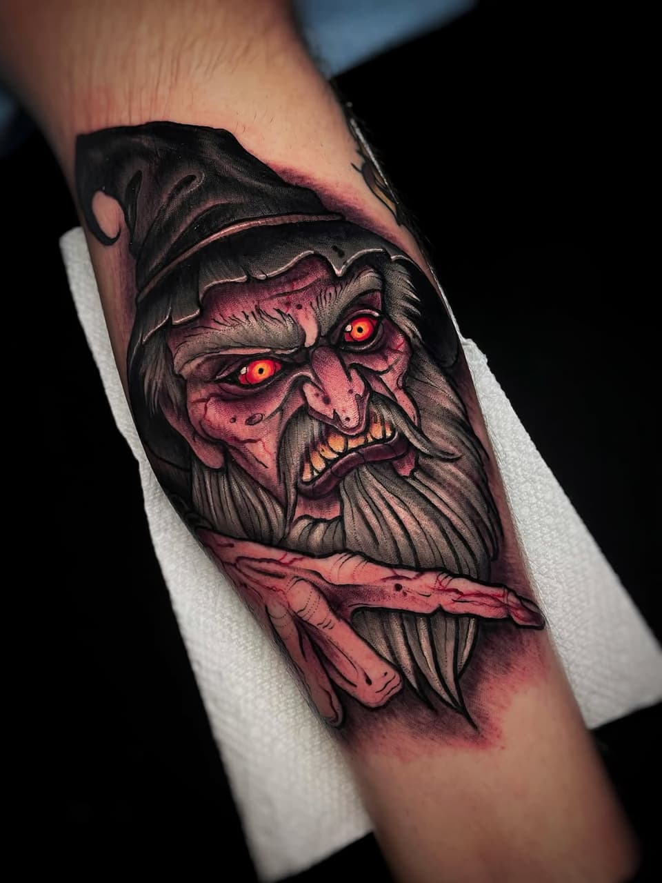 Demonic bearded face with glowing red eyes and exposed teeth on upper arm, rendered in pink, black, and orange tones with shading.