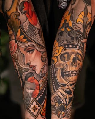 Pair of forearm tattoos featuring a woman's profile with red birds and ornamental crowns with skulls, rendered in orange, red, and black ink.
