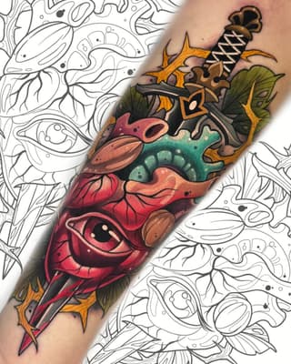 Colorful dagger tattoo on forearm featuring a red dragon head with green scales, golden crossguard, and wrapped handle against decorative background.