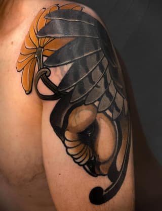 A large shoulder tattoo featuring a scorpion with black and grey body, tan claws, and an orange flower held in its tail against skin.