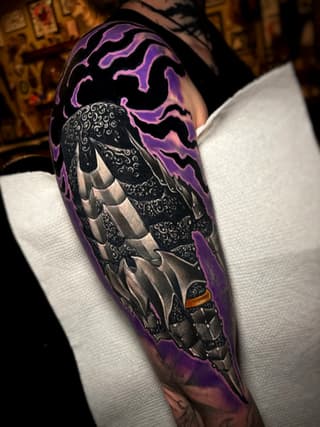 Colorful sleeve tattoo featuring a detailed moth with ornate patterned wings, purple lightning background, and small mechanical elements, on a person wearing white sleeve.