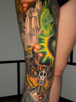Colorful leg sleeve tattoo featuring a skull with moth wings, glowing portal, tower, and botanical elements in orange, green, and yellow.
