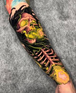 Colorful skull and skeleton ribcage tattoo on forearm featuring yellow, green, pink, and black ink with decorative flames at the wrist.