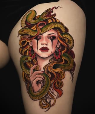 Medusa-inspired portrait tattoo on upper arm featuring a woman's face with serpents in her hair, rendered in gold, green, red, and burgundy tones.