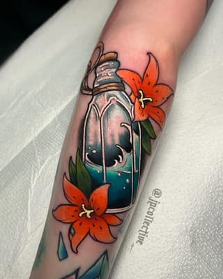 Colorful tattoo on a forearm featuring a glass bottle with blue liquid, orange flowers, and decorative leaves in red, green, teal, and gold tones.