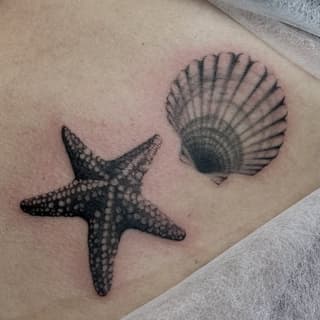 Starfish and scallop shell tattoo in black ink on pale skin, positioned on the upper arm or shoulder area.
