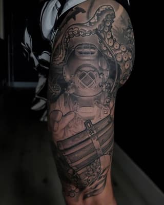 Full sleeve tattoo on upper arm and shoulder featuring an octopus with tentacles, a diving helmet, and mechanical elements in black and gray ink.
