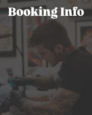 Tattoo artist with visible arm tattoos working on a client's leg during a booking consultation in a studio setting.