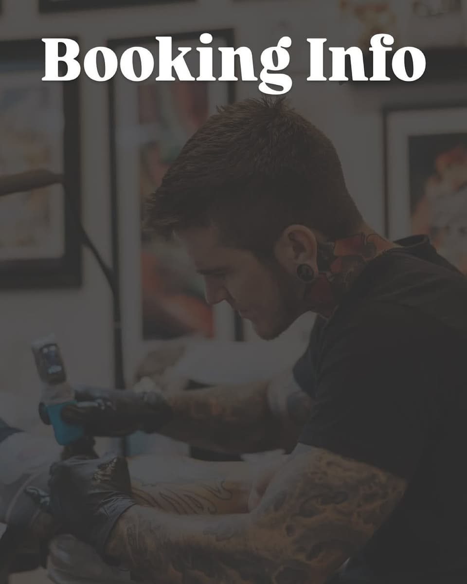 Tattoo artist with visible arm tattoos working on a client's leg during a booking consultation in a studio setting.