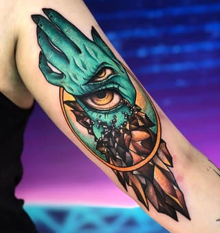 Dragon eye tattoo on upper arm featuring turquoise scales, golden iris, and geometric shattered pattern below in orange and brown tones.