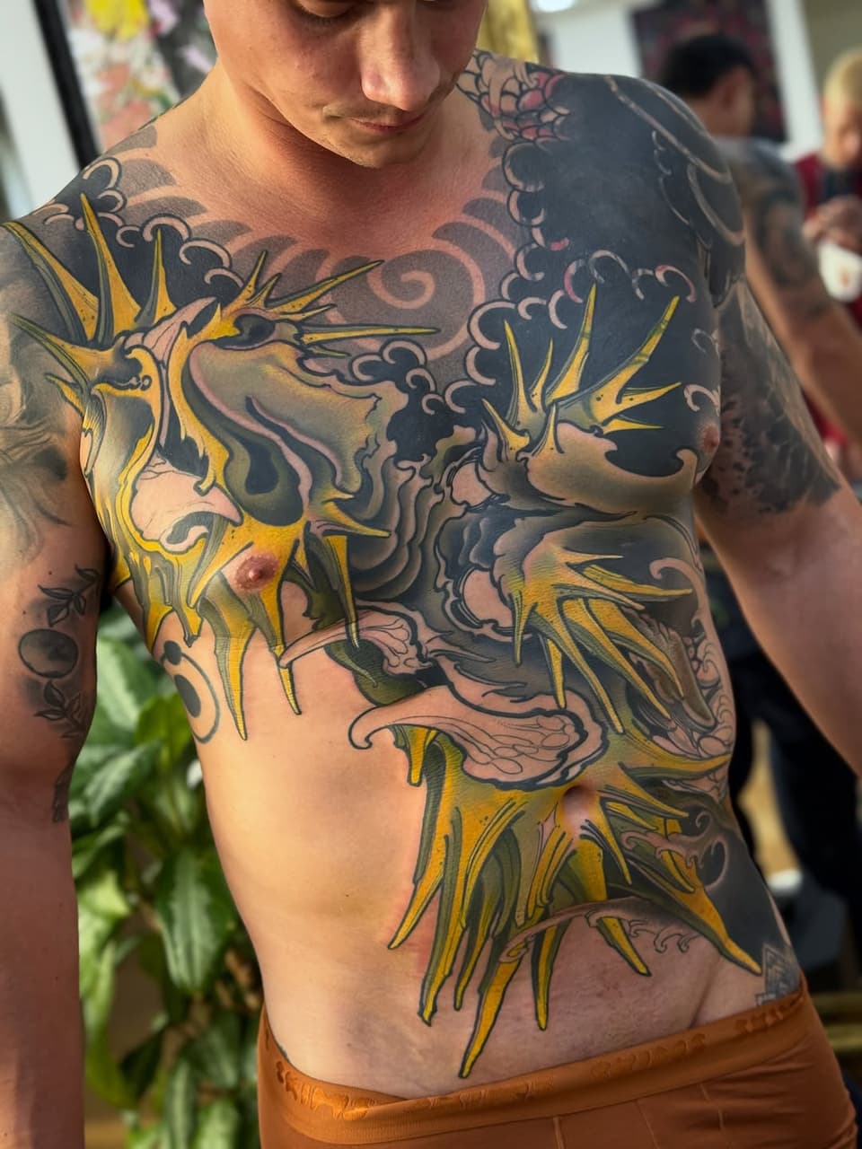 Chest and torso tattoo featuring yellow sunflowers with dark ornamental scrollwork and floral designs in black and purple ink.